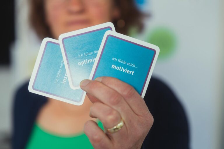 Bettina Engelbrecht zeigt Stärkekarten in der Hand, darauf stehen Begriffe wie motiviert, optimistisch und inspiriert.